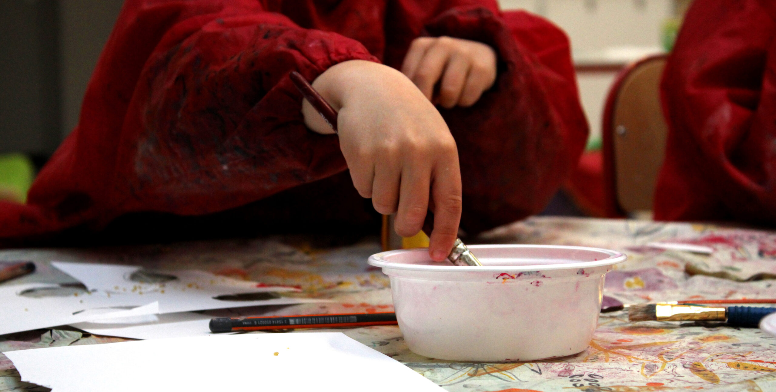 Main d'un enfant en train de prendre de la peinture avec un pinceau